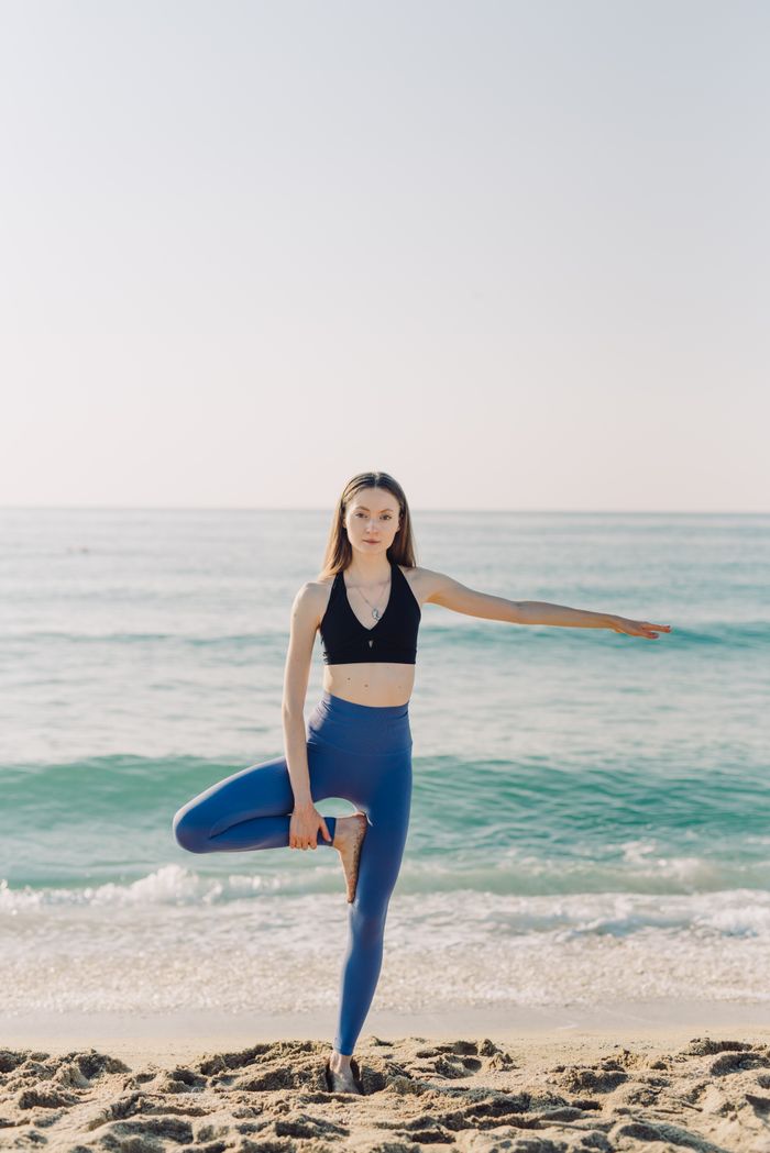services-07 Woman in a yoga pose by the sea, embracing a healthy lifestyle outdoors.